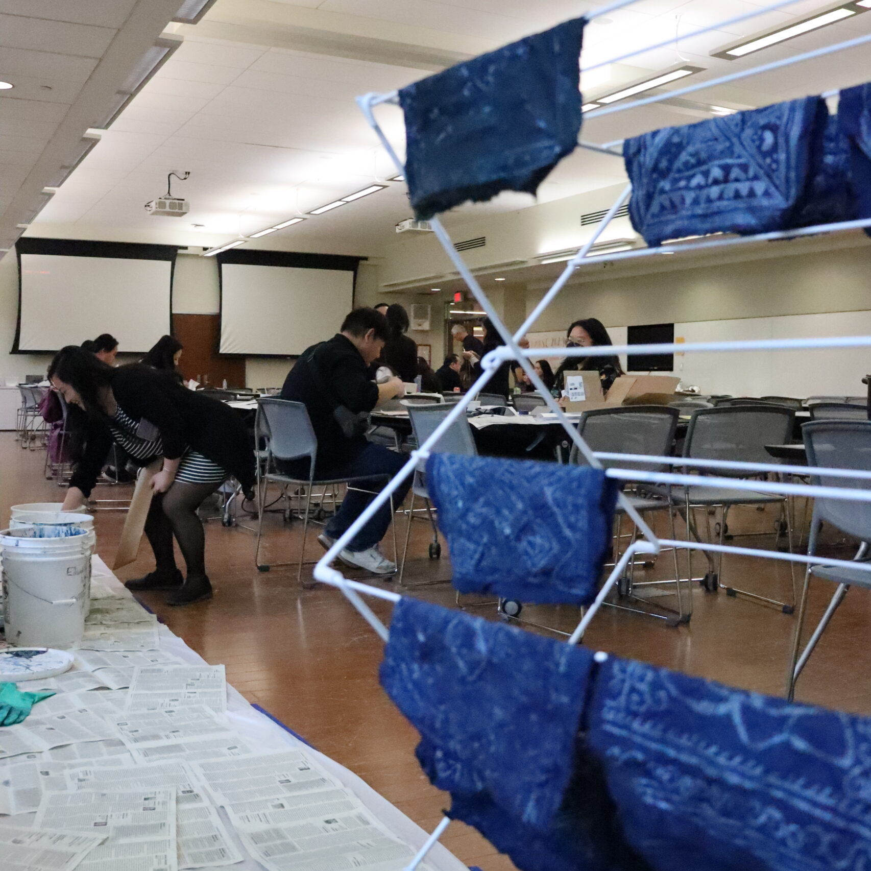 A drying rack with blue fabric squares hanging on it in a classroom.