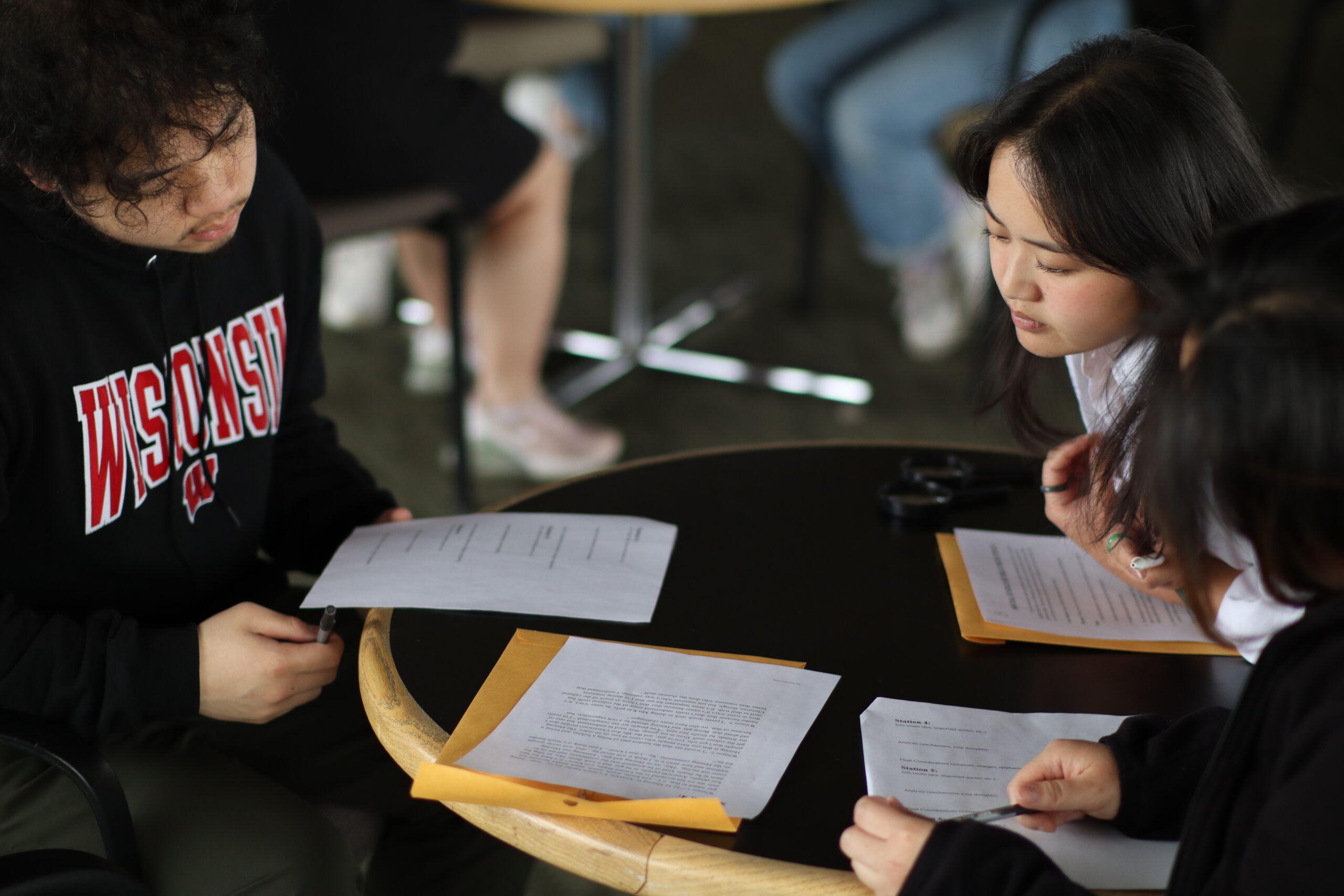 Two students look down at the same piece of paper together.